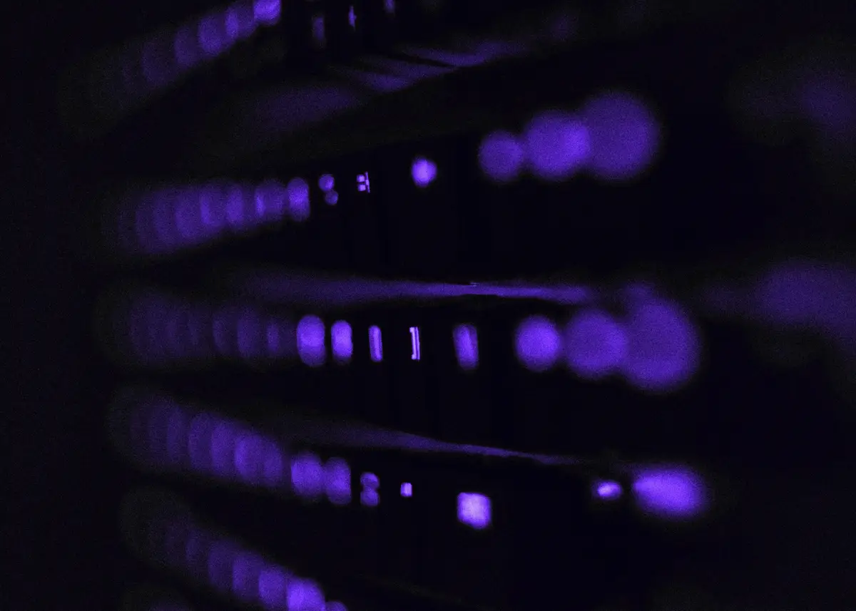 Primer plano de luces de estado de un rack de servidores que brillan en violeta en una sala oscura.